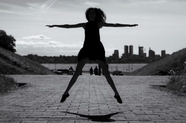 A dynamic black and white silhouette of a woman jumping with arms outstretched in Tallinn, Estonia.