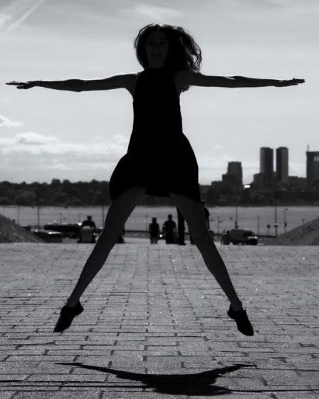 A dynamic black and white silhouette of a woman jumping with arms outstretched in Tallinn, Estonia.
