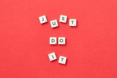 Motivational phrase 'Just Do It' spelled with Scrabble letters on a red background.
